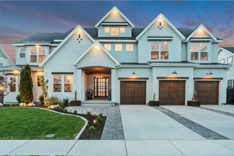 A white house with multiple windows and a driveway at dusk.