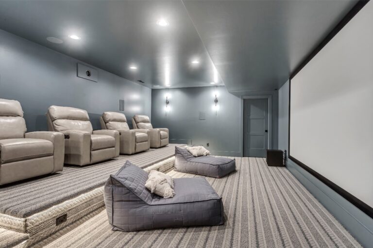 The room is a cinema with reclining seats and an empty screen.