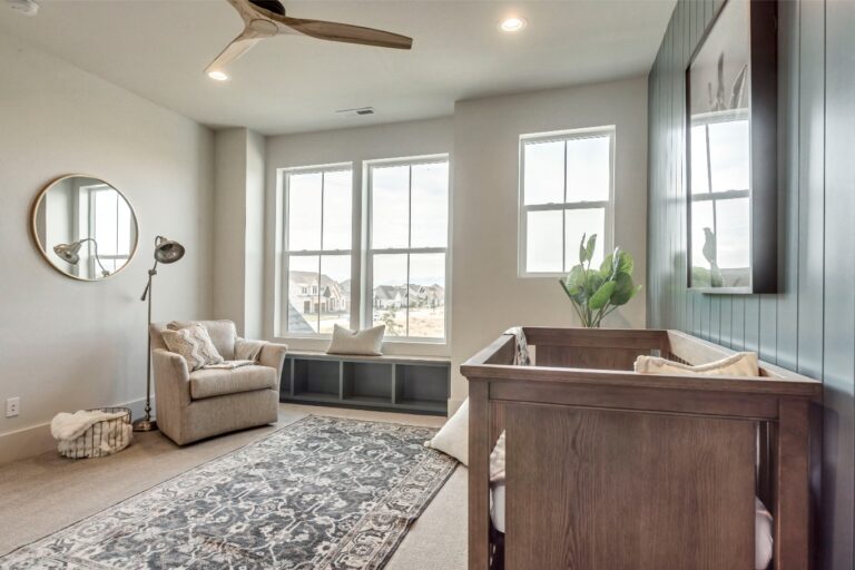 The room is a modern space with white walls and large windows allowing natural light to fill it.