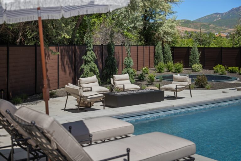 A pool surrounded by chairs and a fire pit with mountains in the background.