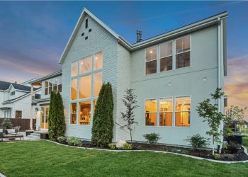 A white house with many windows and a lawn at dusk.