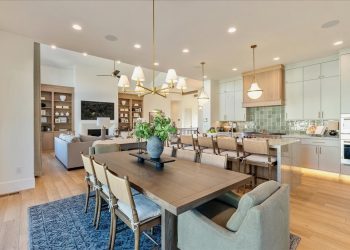 The room is white and has a dining table surrounded by chairs with brown seats.